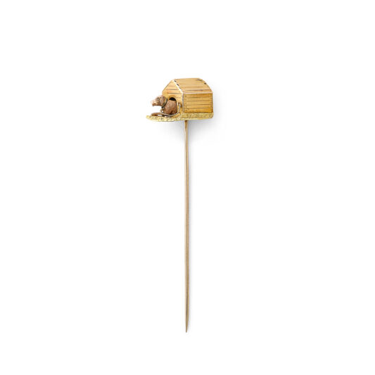 gold three-dimensional stickpin of a dog in its kennel